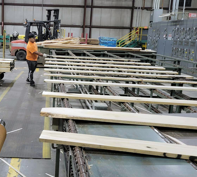 employee handles boards on conveyor